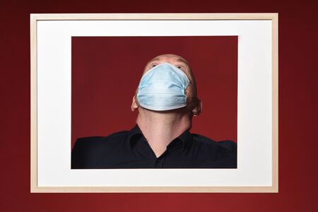 picture of a portrait of a man with mask look up on a red background