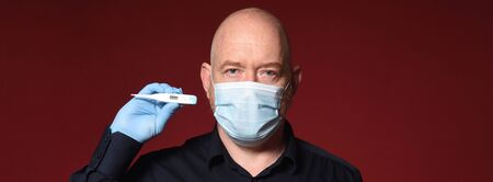 portrait of a man with gloves, mask and  thermometer on a red background