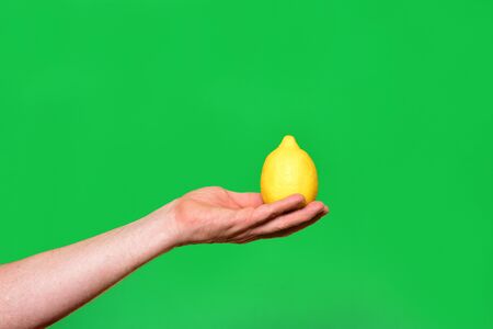 hand holding a lemon on green backgroundの写真素材