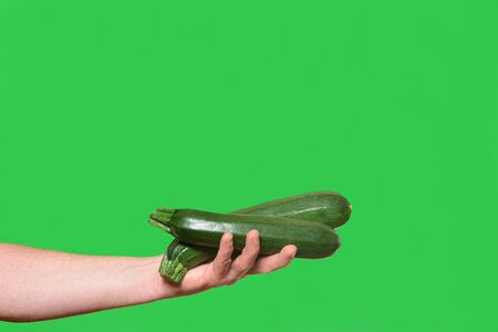 hand holding a zucchini on green backgroundの写真素材