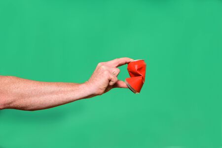 hand crushing a tin can on green background