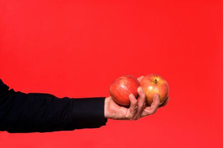 hand holding a two apple on red background