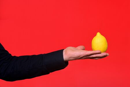 hand holding a lemon on red backgroundの写真素材