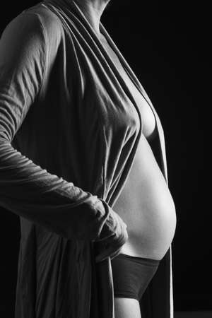 closeup of a pregnant belly, side view, with shirt on black background, 6 months,の写真素材