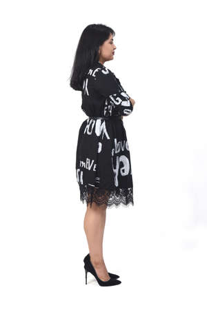 sideways of latin woman with dress and high heels on white background, arms crossedの写真素材