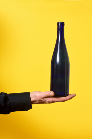 man holding a bottle on yellow backgroundの写真素材