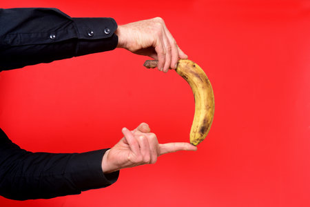 hand honding a banana on red backgroundの写真素材