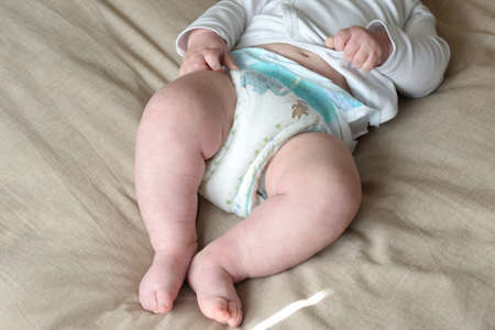 baby in diapers lying on the bed