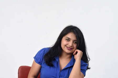 Latin American woman sitting on a chair looking at camera on white backgroundの写真素材