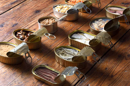 set of cans with fish and seafood on wooden background, elevated view and rear view