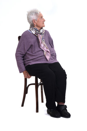 view of a senir woman sitting on chair looking up, serious on white backgroundの写真素材