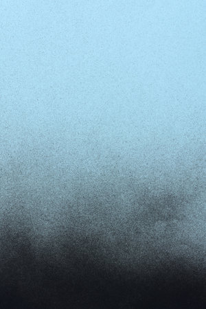 black spray paint on a soft blue colored paper backgroundの写真素材