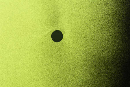 a spray black paint stain on yellow colored paper backgroundの写真素材