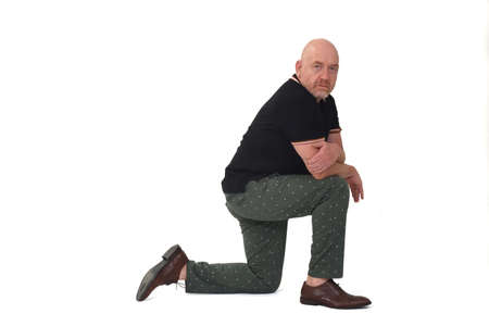 side view and looking at camera of serious man leaning on one knee on the ground on white backgroundの写真素材