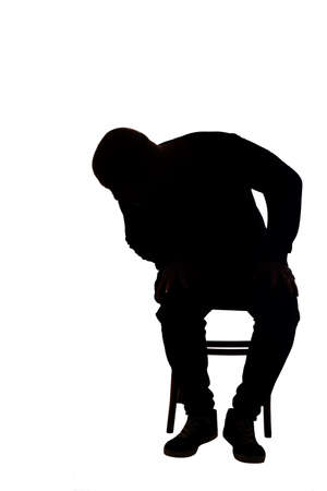 view of the silhouette of a man sitting on chair with casual clothes looking the floorの写真素材