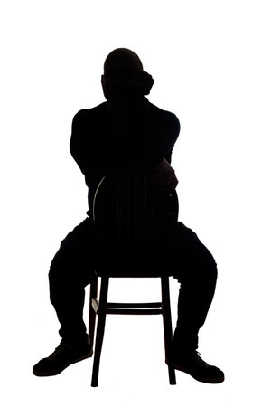 rear view of the silhouette of a man sitting on chair with casual clothes turned chair hand on faceの写真素材