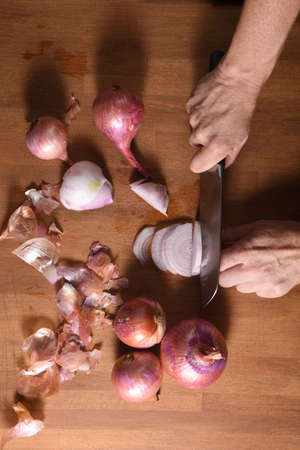 high angle view of a cook peeling an onion on a woodの写真素材