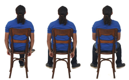 side view of man with ponytail and casual clothing sitting a chair looking at camera and arms and legs crossed on white backgroundの写真素材