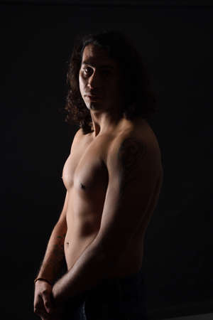 low key portrait of shirtless man looking at camera black backgroundの写真素材