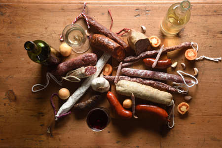 top view of typical spanish sausages and red and white wine on wooden tableの写真素材