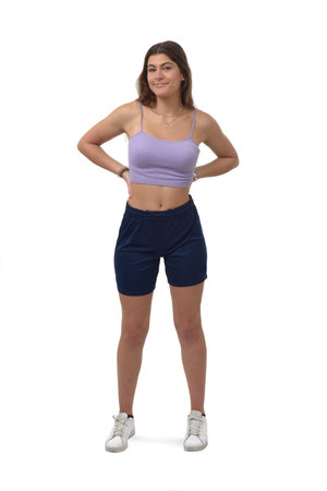 front view of a young girl standing with arm akimbo and looking at camera on white backgroundの写真素材