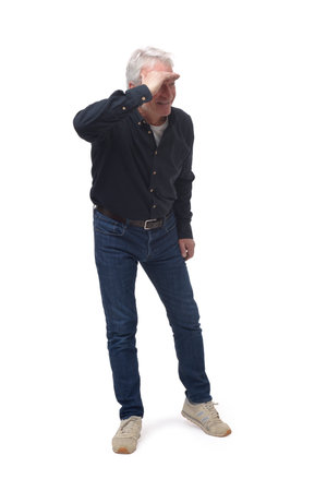 side view of standing man looking away with hand on forehead on white backgroundの写真素材