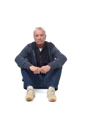 front view of a man sitting on the floor with legs folded and serious and looking at camera on white backgroundの写真素材
