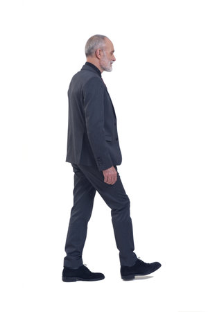 side and back view of a man with suit and tie walking on white backgroundの写真素材
