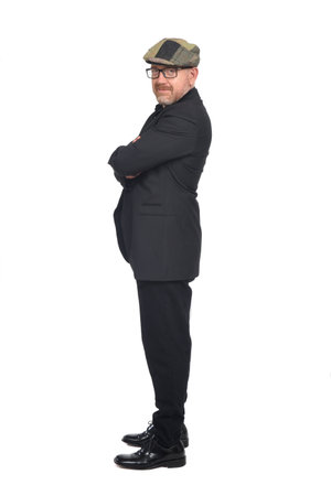 side view of a full portrait a man with suit and cap looking at camera and arms crossed on white backgroundの写真素材