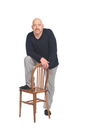 front view of a man in pajamas standing plaiyng with chair and looking at camera on white backgroundの写真素材
