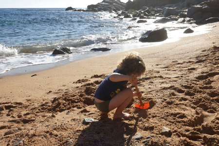 boy playing on the beach with a shovel making a hole in the sandの写真素材
