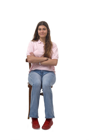 front view of a young girl sitting on chair with arms crossed on white backgroundの写真素材