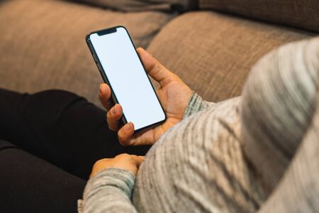 Pregnant white woman using a mobile phone in homeの写真素材