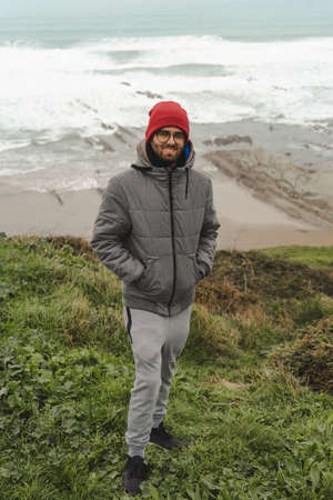 Man on the cloudy coast looking at the camera with warm clothesの写真素材