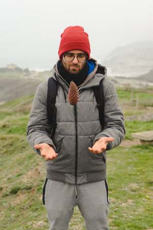 Man throwing a pinecone in the meadow beside the sea