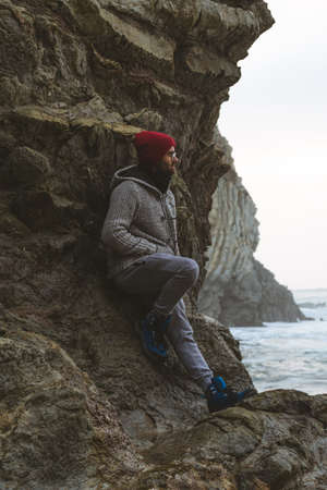 A man on the rocky shore looking out to sea over some rocks.の写真素材