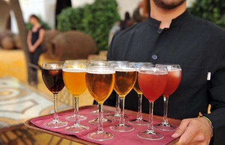 Waiter serving beer and soft drinks at a party of friendsの写真素材