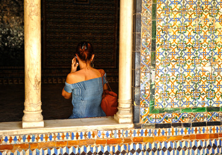 Cultural tourism, woman back on a guided audio tour, Palace of Seville, Andalusia, Spainの写真素材