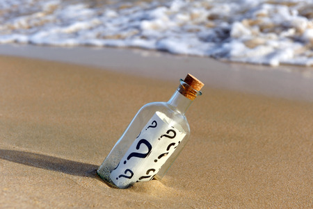 Bottle with doubts on the beachの写真素材