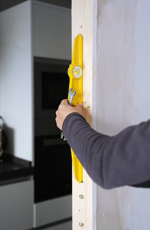 Carpenter using level tool to check the verticality of the new door frameの写真素材