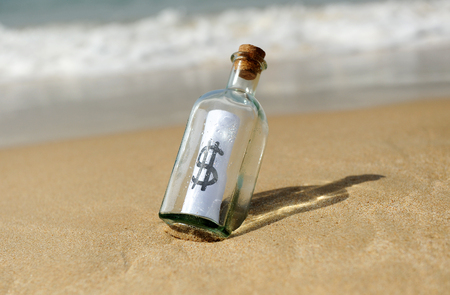 Bottle with dollar sign on beachの写真素材