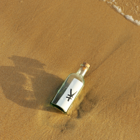 Yen symbol in a bottle on the sand, money conceptの写真素材