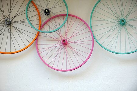 Old bicycle wheels colorful on the wall of a rental and repair store, hipster decorative trend...