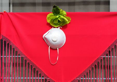 Personal protection face mask with FFP2 particle filtration on a red shawl. Time of Covid-19 in Seville, Spainの写真素材
