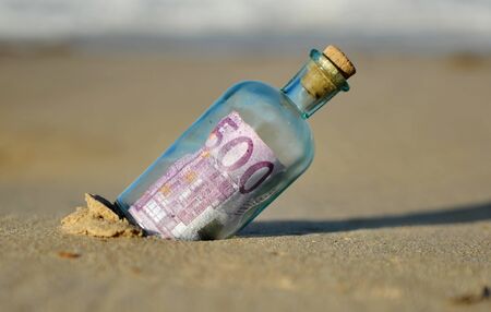 Five hundred (500) euro bill in a bottle found on a beach in southern Europe with waves in the background. Tax haven concept, currency trafficの写真素材