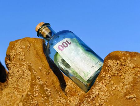 One hundred (100) euro banknote in a bottle found on the rocks of a beach, currency trafficの写真素材