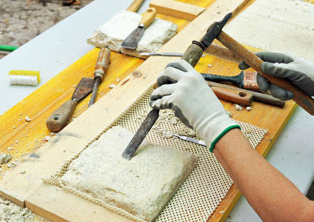 Removal by hand of the mortar of an old tile with a spatula. Restoration and conservation of ancient ceramicsの写真素材
