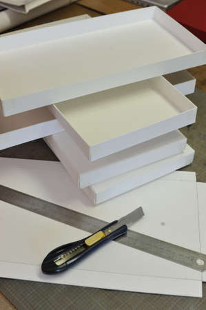 Handmade white cardboard boxes to line with paper. Boxes for gifts. Cutter and metal rulerの写真素材