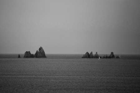 black and white background of a sailboat sailing in the distanceの写真素材