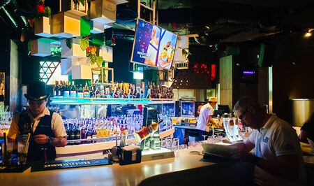 Bangsar, Kuala Lumpur / Malaysia - July 5, 2019: The scene of bar counter in W.I.P Cafe & Restaurant at Bangsar Shopping Centre. The bar tender is cleaning glasses while a customer is looking at menuのeditorial素材